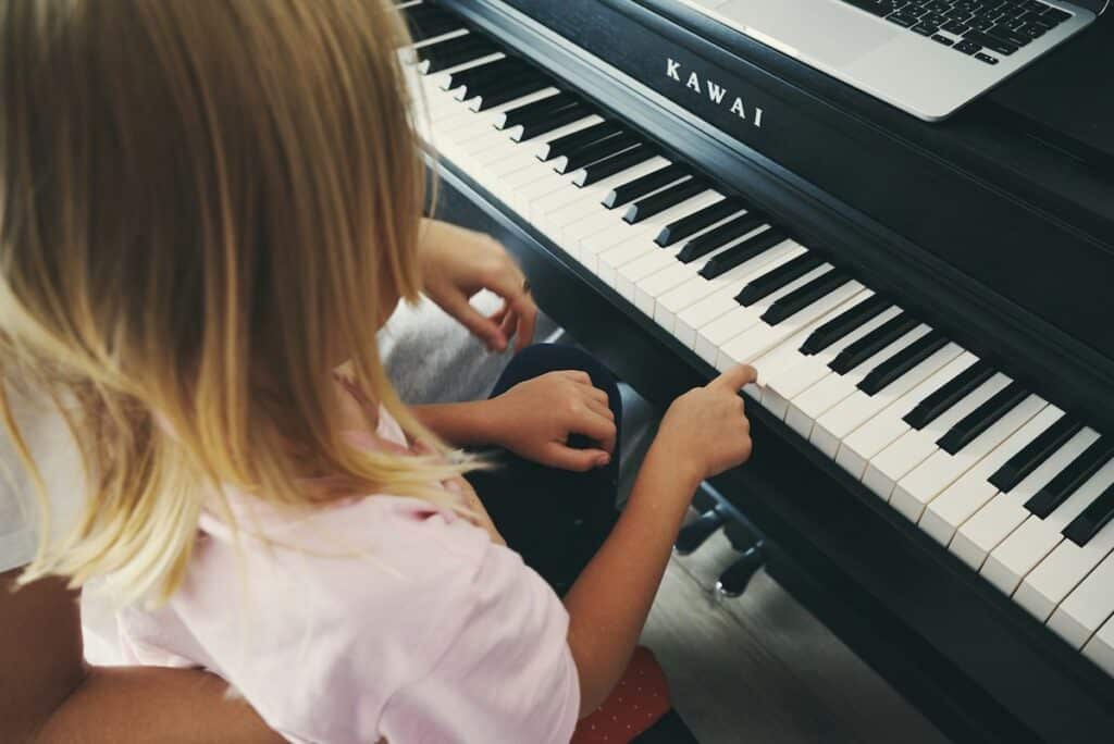 Ein Kind berührt fasziniert die Tasten eines schwarzen Klaviers und entdeckt die Magie der Klänge, beim Erleben von Live-Musik in Wien, kuratiert für Familien auf fini.wien.